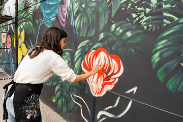 Female artist painting mural on wall