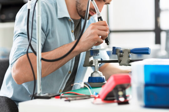 Engineer using drill on circuit board in electronic laboratory