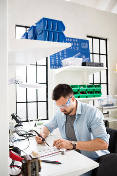Concentrated technician soldering circuit at electronics industry