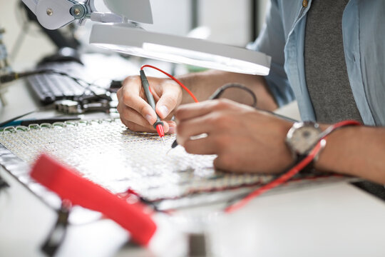 Close-up of engineer soldering circuit at table in electronics industry