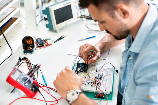 High angle view of technician analyzing circuit board at table