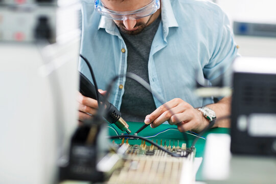 Serious technician working at table in electronics industry
