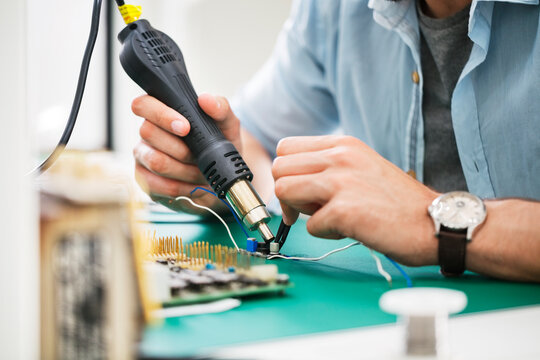 Midsection of technician working at table in electronics industry