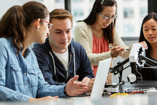Teacher explaining drone while students discussing over laptop in classroom