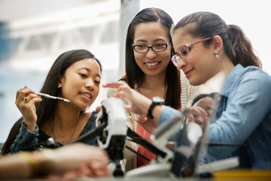 Teacher and students discussing over drone in classroom