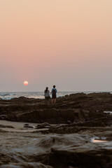 Indian Couples and tourists enjoying the beach and a romantic sunset in Goa, India