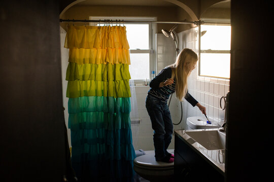 Girl cleaning flush with toilet brush in bathroom