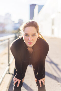 Portrait of tired woman bending by railing in city