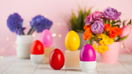 Fototapeta na wymiar Easter colorful eggs on the background of spring flowers. Bright Easter concept. Copy space.