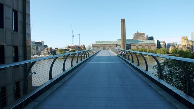 Lockdown in London, gimbal walk across deserted Millennium Bridge with the Tate Modern over the Thames River, during the Coronavirus pandemic 2020.