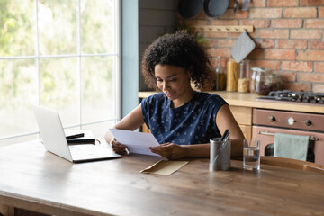 Satisfied African American woman reading letter, good news, money refund, businesswoman working...