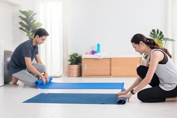 Obraz premium Asian young couple exercise and play yoga together at home background.Concept of Exercise during the quarantine at home for preventing coronavirus and covid-19 infection.