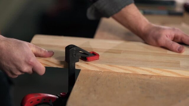 close-up of male hands clamping the board with carpentry clips