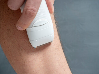 Close-up of a man removing hair from his leg using an electric depilator. Lots of leg hair. The...