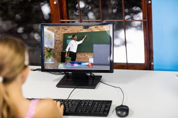 Female student having a video call with male teacher on computer at school