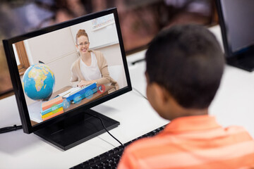 Male student having a video call with female teacher on computer at school