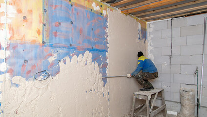 A worker plasters the walls in the room.