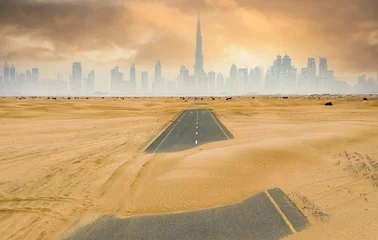Foto op Canvas View from above, stunning aerial view of a deserted road covered by sand dunes with the Dubai Skyline in the background. Dubai, United Arab Emirates. © Travel Wild