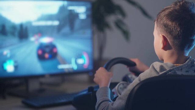 a small boy plays computer games, a child plays a racing game on a car simulator. concept of video games The newest gadgets