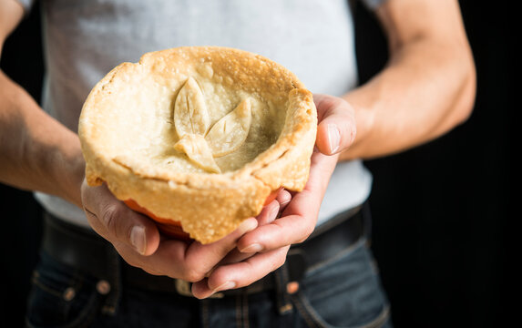 Midsection of man holding chicken pot pie against black background