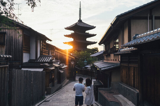 Rear view of couple photographing yasaka pagoda while standing on walkway