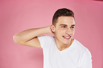 Obraz premium A man in a white t-shirt gestures with his hands emotions pink background studio cropped view