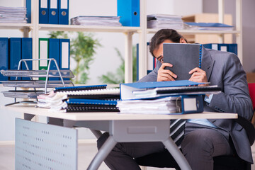 Young male employee unhappy with excessive work in the office