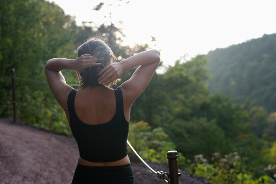 Rear view of woman tying hair while standing against mountains