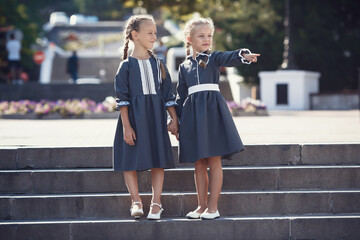 Charming little girls in retro dress walking in town on a sunny summer day