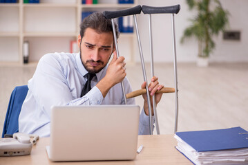 Young leg injured male employee working in the office