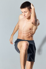 Fototapeta na wymiar sport man in shorts doing exercise leaning forward on gray background 
