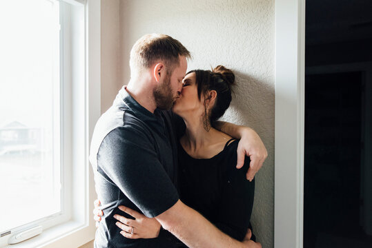 Affectionate Couple kissing while standing by window at home