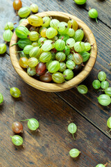 Ripe gooseberry in a wood plate, place for text, top view