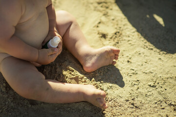 Sandy beach, baby on the beach, bright sun, baby sunbathing, bare legs, hard shadows, sun shining brightly, baby in summer
