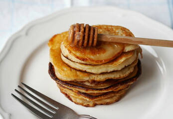 Pancakes with honey on a white plate. Traditional treat for Shrovetide.