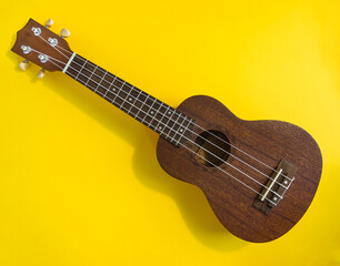 Ukulele on bright yellow background.Overhead photo of ukulele.