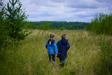 Fototapeta na wymiar summer forest, field, nature,, two children in blue jackets stand in a field, field in June