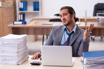 Young male employee unhappy with excessive work in the office