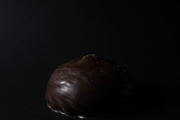 Marshmallow with chocolate icing on a black background close-up.