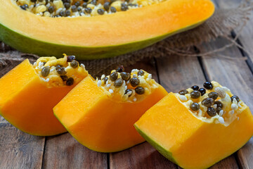 Fresh slices of papaya fruit with sackcloth on wooden background.Tropical fruit.
