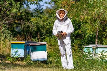 Portrait of happy male beekeeper holding smoker while standing at apiary