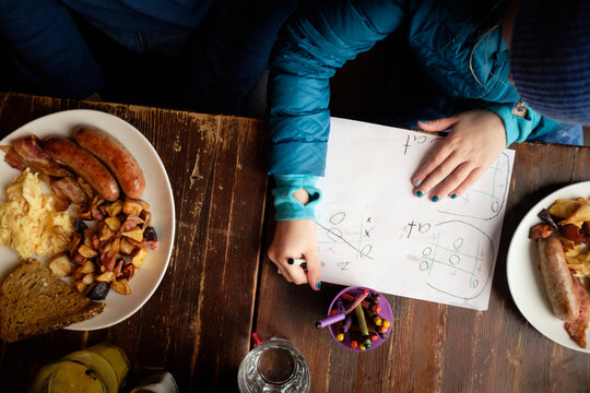 High angle view of girl studying while sitting by food on table at home