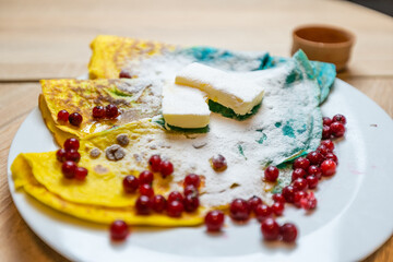 colored pancakes with berries, butter and honey