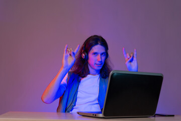 Student or programmer at a laptop, portrait in neon tinting. Funny guy geek writes code.