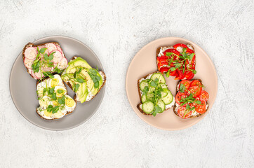 Different sandwiches with vegetables, avacado, egg and microgreens on plates on a light background