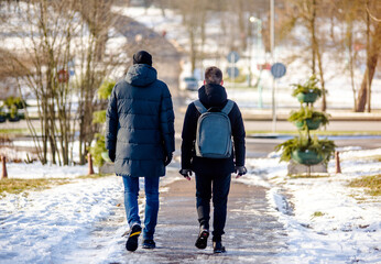 Two boy walk along the path in the winter Park
