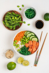 Poké bowl with fresh salmon, rice, chukka salad, edamame beans, carrots and cucumber. Bowl of healthy food on white background 