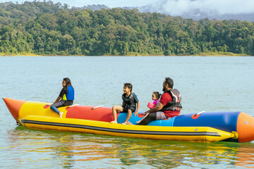Family enjoying water activities on banana boat at the Kenyir Lake, Terengganu, Malaysia.