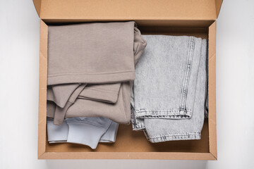 Delivery of clothes in paper box. Trendy clothes on white background