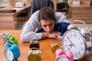 Young male employee sleeping in the office in time management co